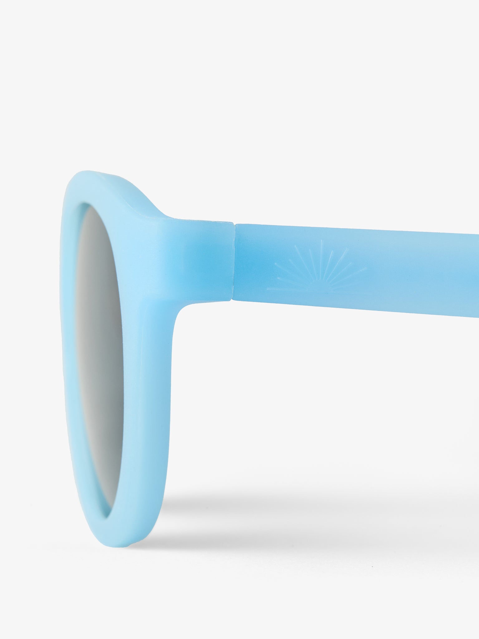 Close up of the side of a pair of blue baby sunglasses with half sun petit peepers logo